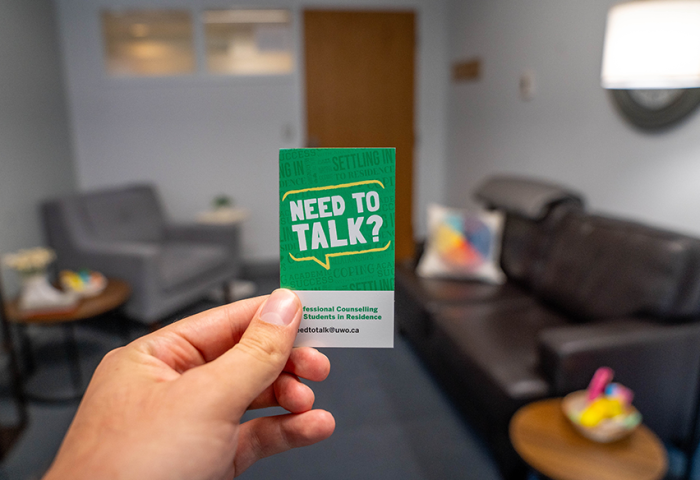 Hand holding up a residence counselling contact card