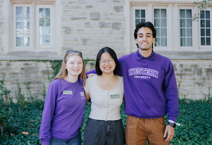 Three student leaders out front of a residence building